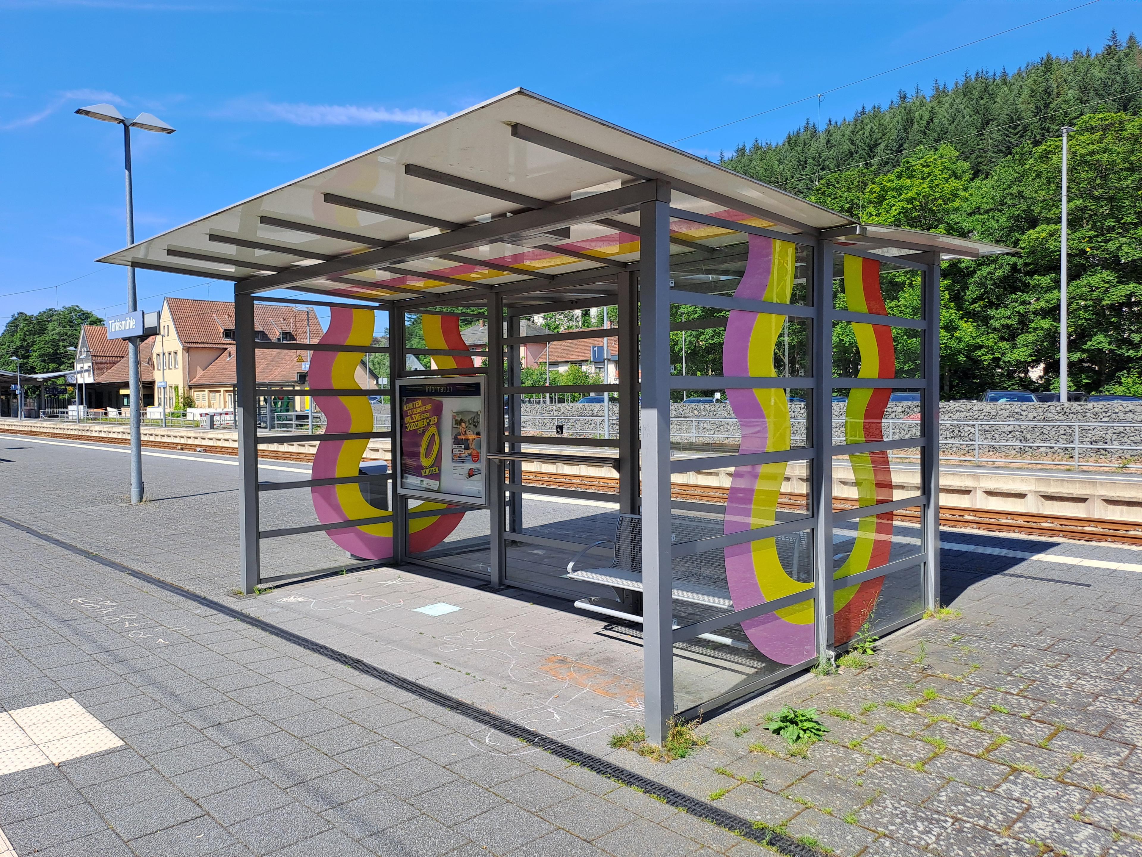 Blick auf ein neues Wetterschutzhäuschen mit Wellenmuster am Zukunftsbahnhof Türkismühle.