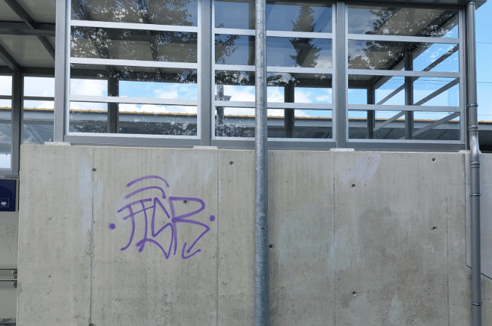 Blick auf die graue, teilweise beschmutzte Außenfassade des Bahnhofs.