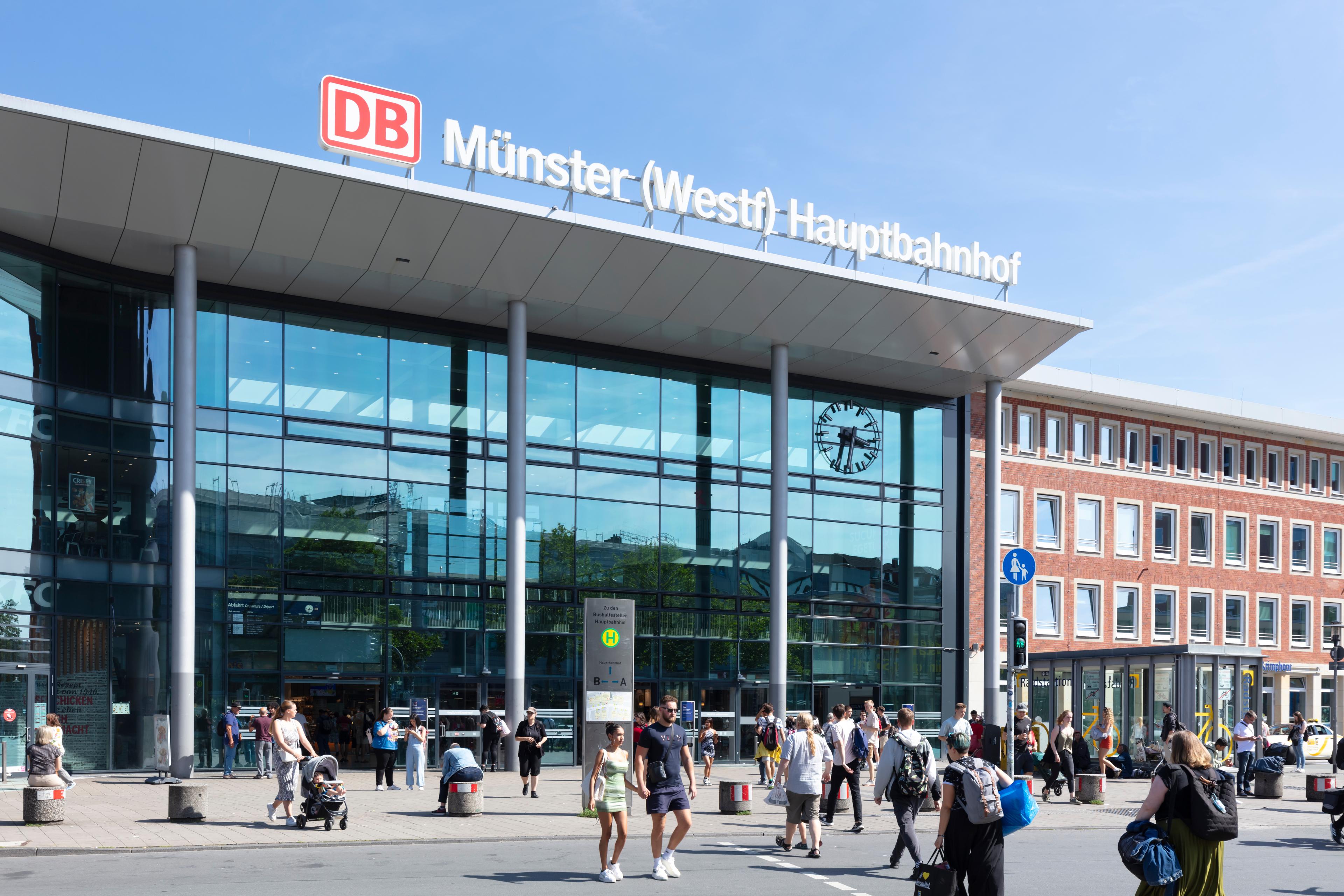 People walk in front of Münster (Westf) Hauptbahnhof.