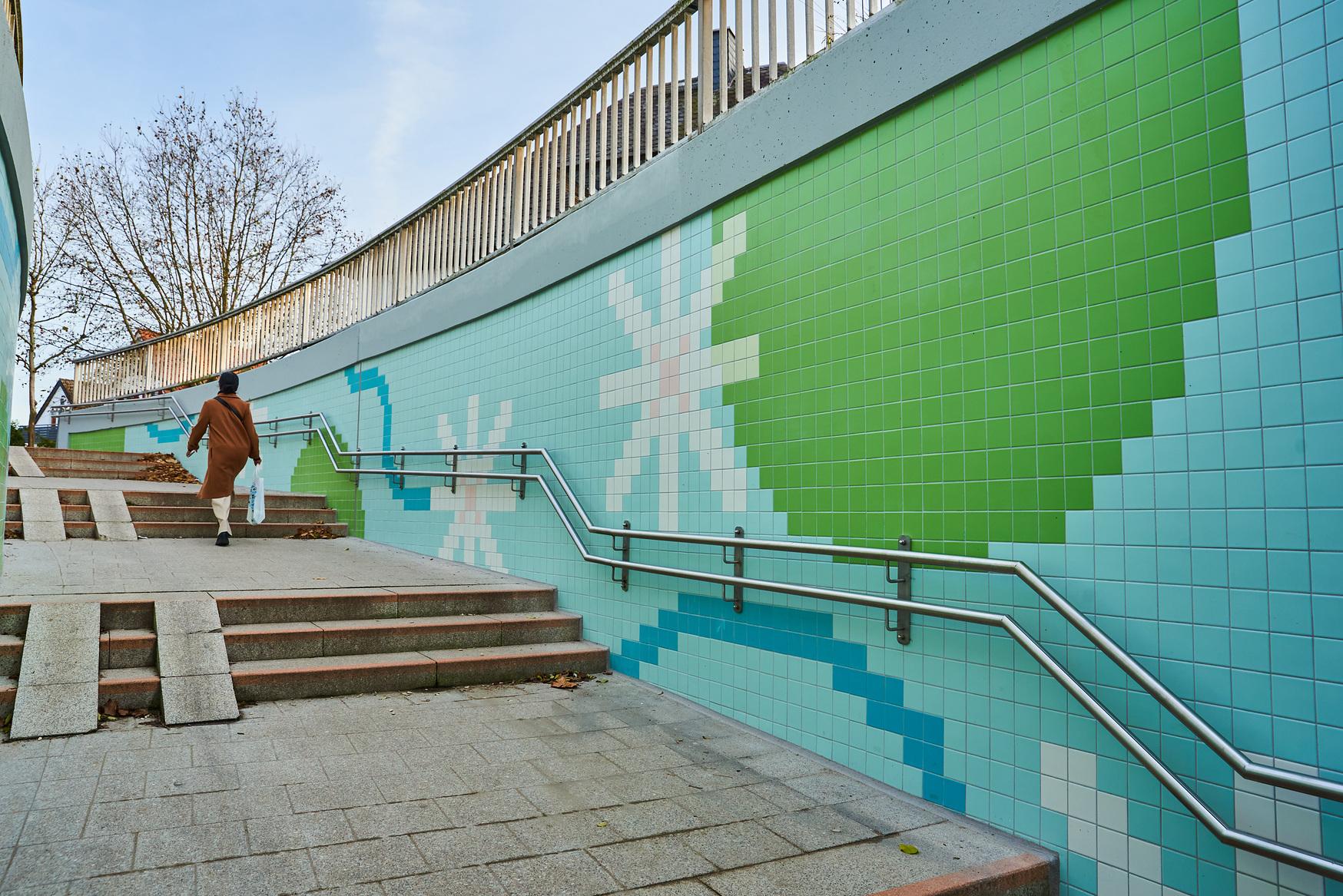 Eine Person läuft den neugestalteten Treppenaufgang am Bahnhof Mörfelden hoch.