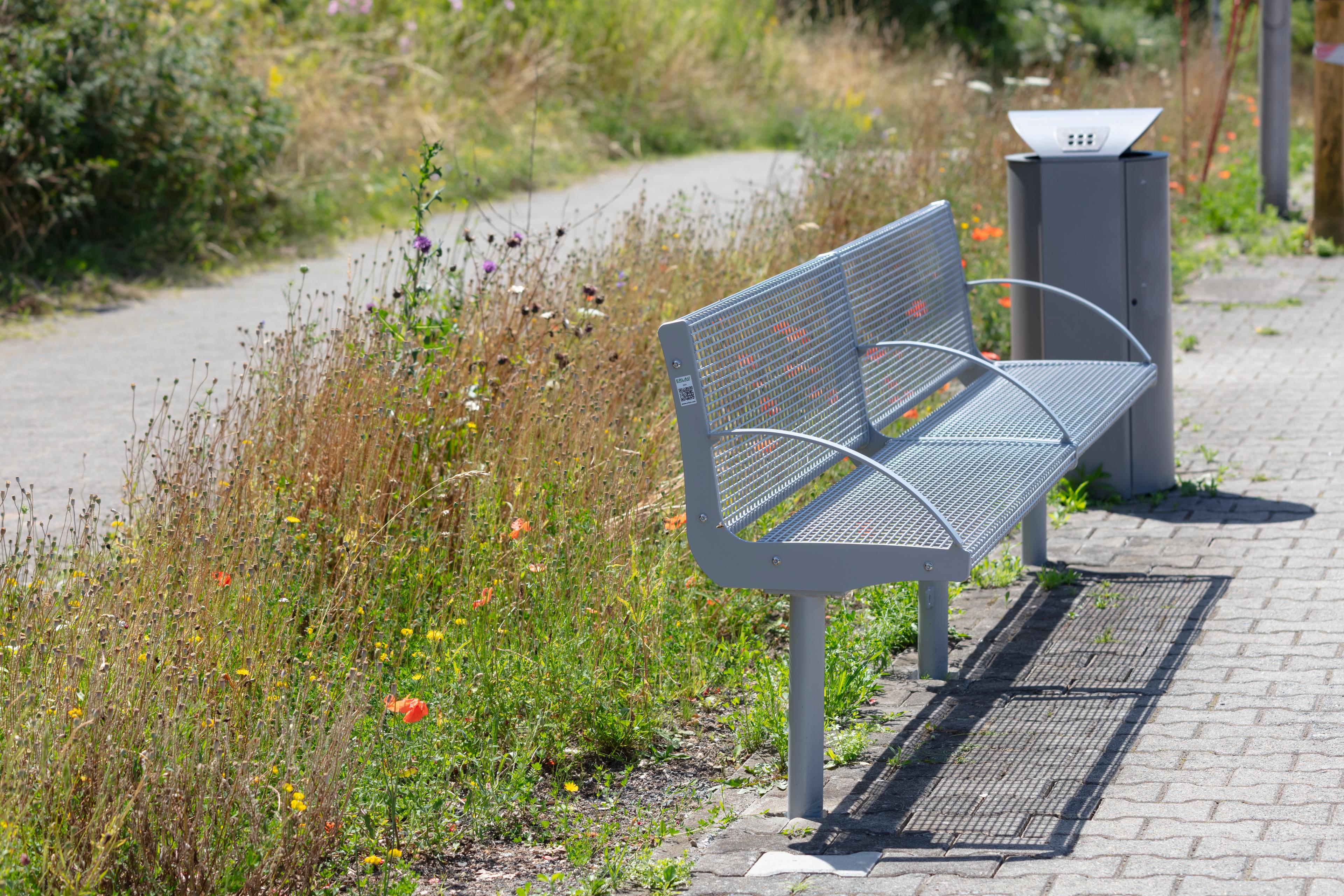 Wildpflanzen hinter Sitzgelegenheit am Bahnsteig