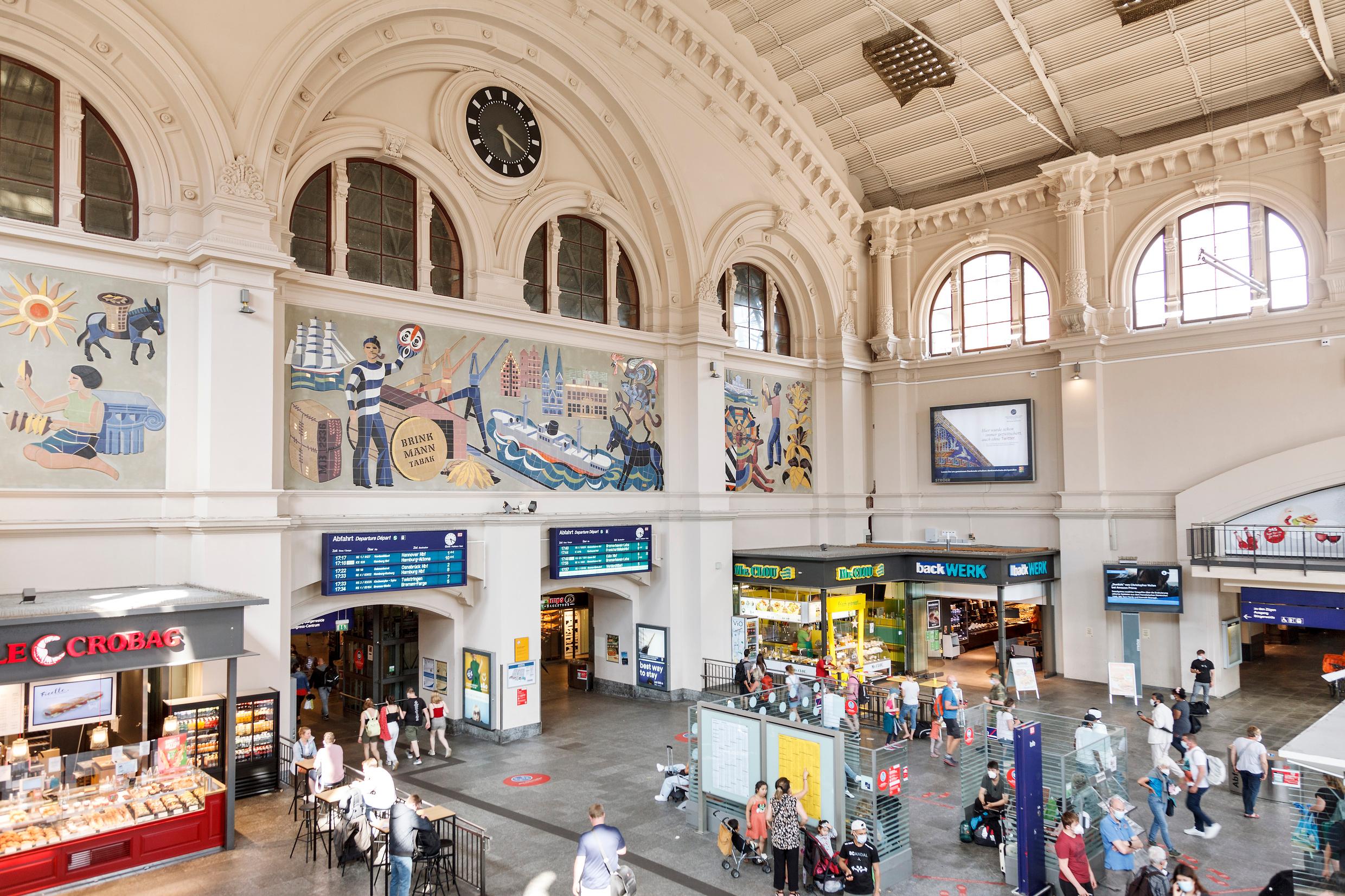 Die Innenansicht des Hauptbahnhofs in Bremen mit Geschäften und Informationstafeln.