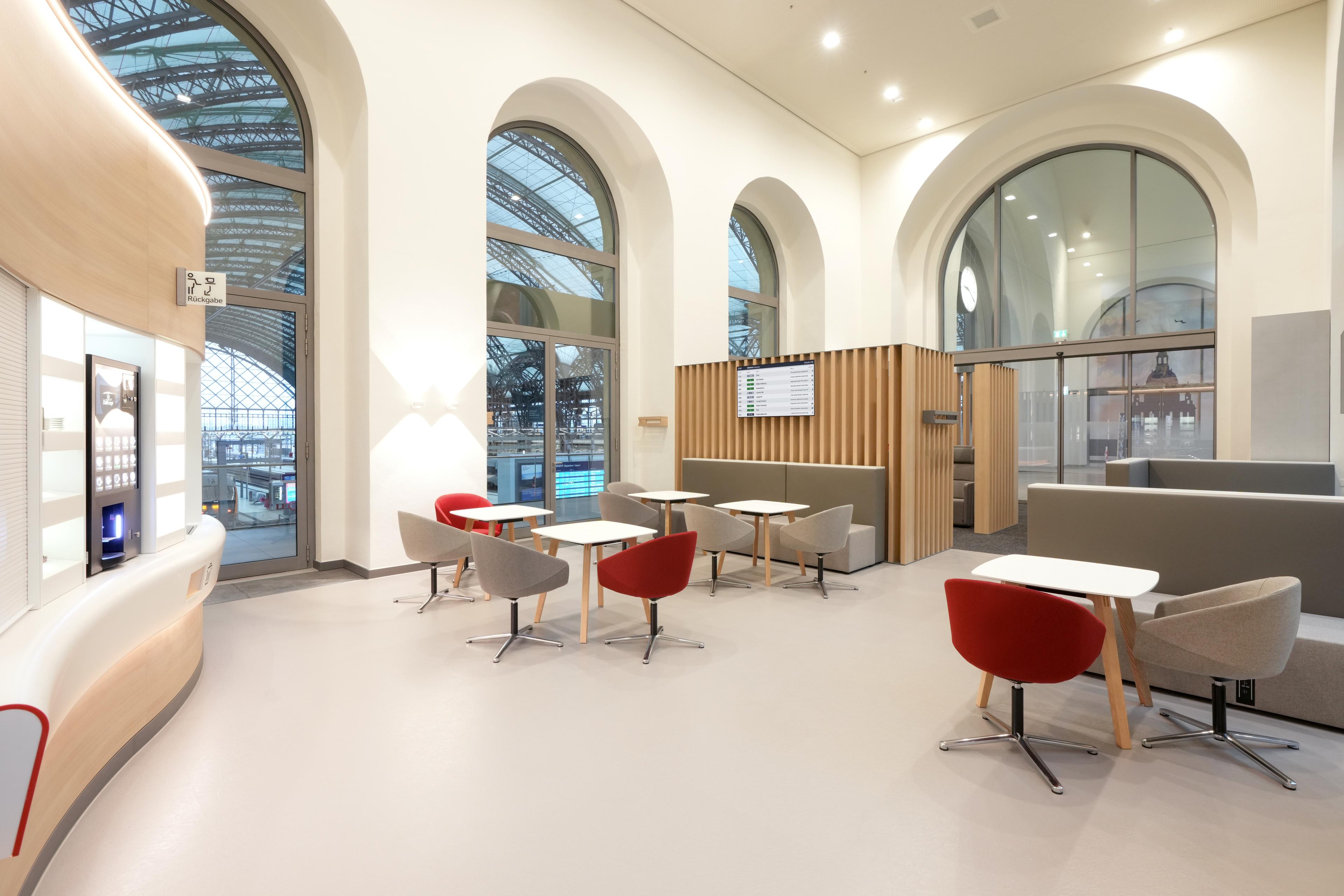 Various seating areas with round chairs, tables and benches with views of the platforms from large windows.