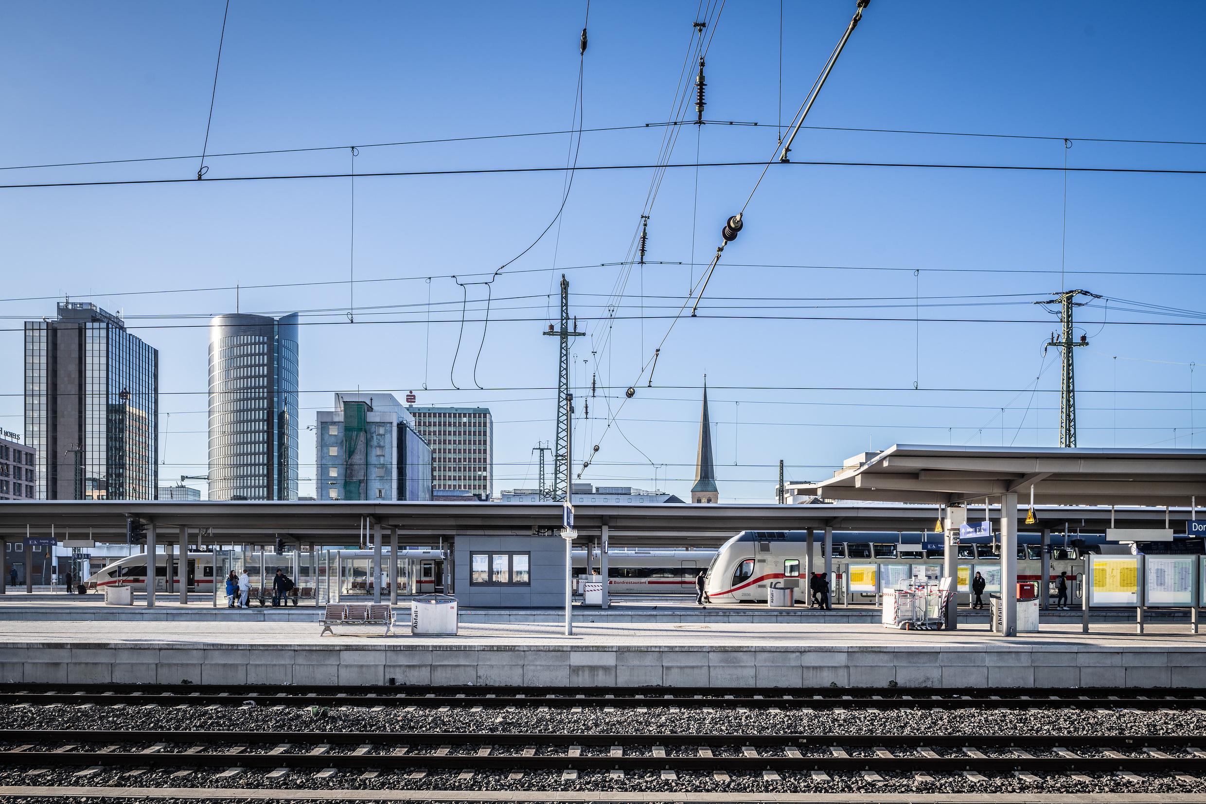 Several platforms at the station Dortmund Hauptbahnhof with high-rise buildings in the background.